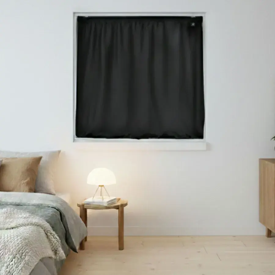 Sort Instant Night-gardin spændt op i en kvadratisk vindueslysning over en seng og et natbord med lampe